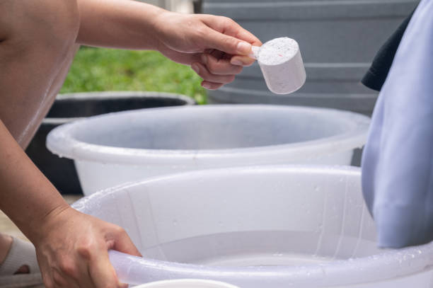 istock Woman while adding washing powder into basin for washing cloths. 2165628894
