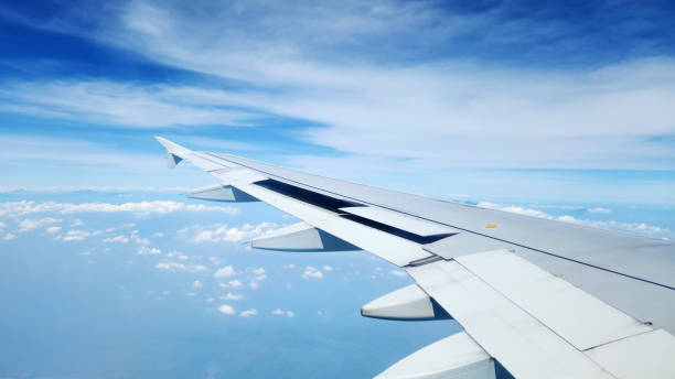 istock Blue sky and clouds and airplane wing seen from airplane cabin window 2165629022