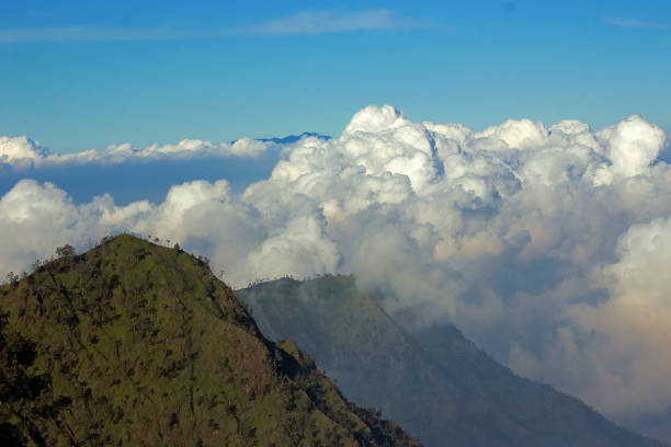 A hill covered by clouds formation under the blue sky.