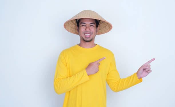 istock Asian farmer smiling and pointing beside him 2165635135