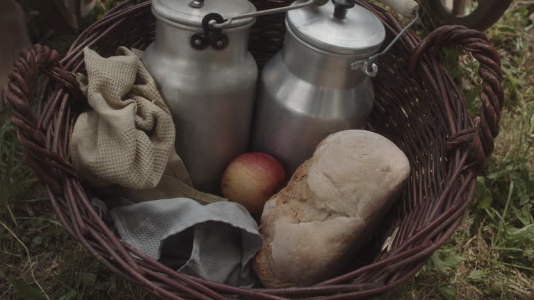 Close up shot of grabbing an apple out of a wicker basket, handheld camera shot. Bread and two cans of milk in the basket.