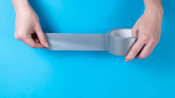 istock Woman holding silver scotch tape on blue background. 2165637986