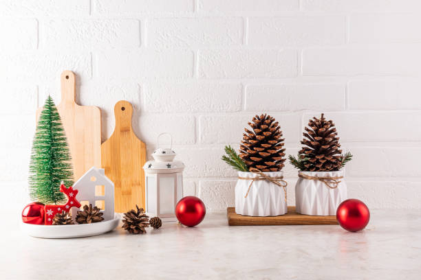istock Home Countertop Kitchen Christmas decorations, balls, a mini Christmas tree, a lantern, a cones in a bowl, large cedar cone in a planter. Front view 2165639040