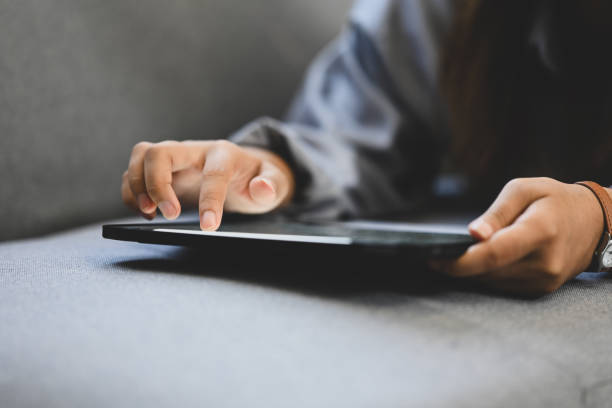 istock Close up image of unrecognizable woman hands using digital tablet, lying on couch at home 2165640134