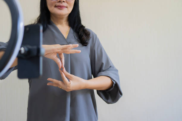 istock Happy mature Asian woman with disability using cell phone for broadcasting with copy space. 2165642256