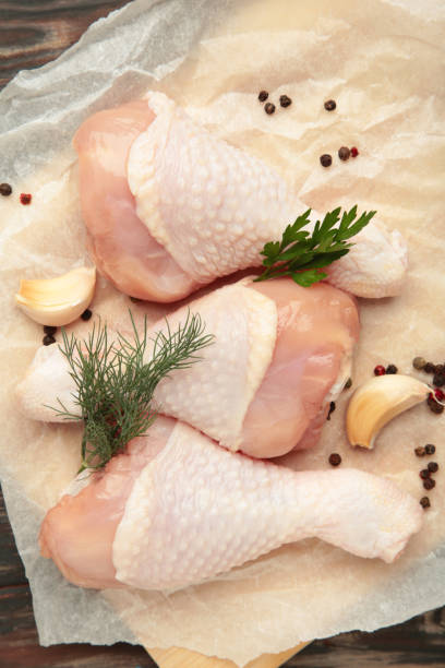 istock Raw chicken drumsticks with spices on cutting board on brown background. Top view. Vertical photo 2165642379