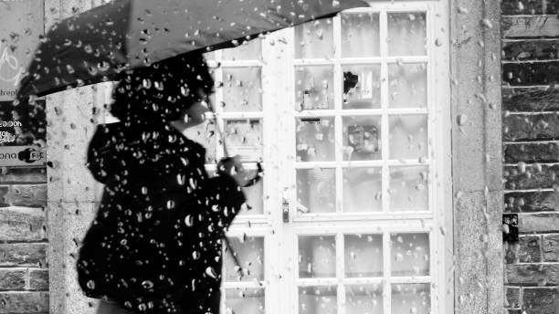 Black and white high contrast rain drops on window with out of focus parking lot landscape background