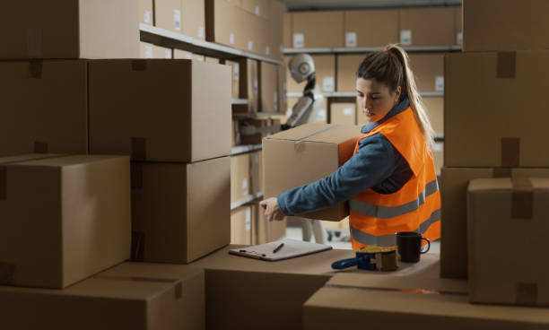 istock Woman and android robot working together in a warehouse 2165649840