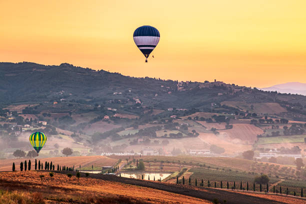 Umbria, Italy - August 4, 2024: Hot air balloons flying over the hills at sunrise