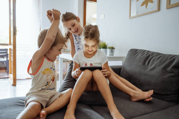 istock Three siblings using smart phone to play mobile game and celebrating winning 2165660197