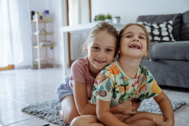 istock Preschool sisters hugging and looking at camera 2165662004