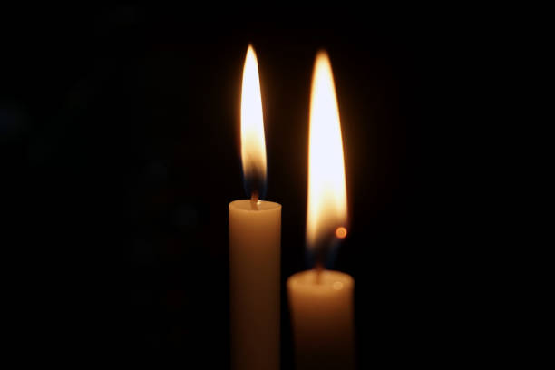istock candle light burning in dark place isolated on black background 2165668527