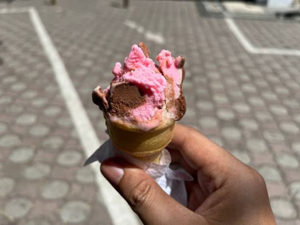 istock Pink strawberry ice cream while being held by hand in the hot sun 2165670105