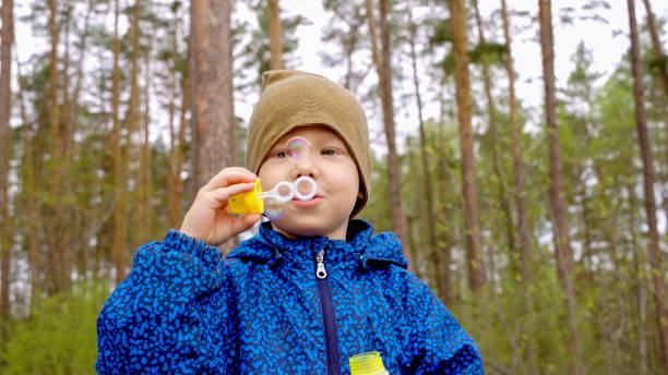 istock A kid blows soap bubbles in the forest. 2165675082