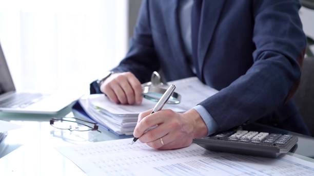 istock Businessman using a calculator and magnifying glass while analyzing financial documents at desk in modern office. Audit and taxes in business 2165675173