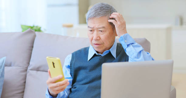 istock elderly male laptop mobile scammed 2165679415