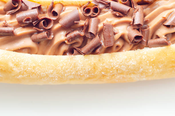 A chocolate covered doughnut with chocolate chips on top, eclair