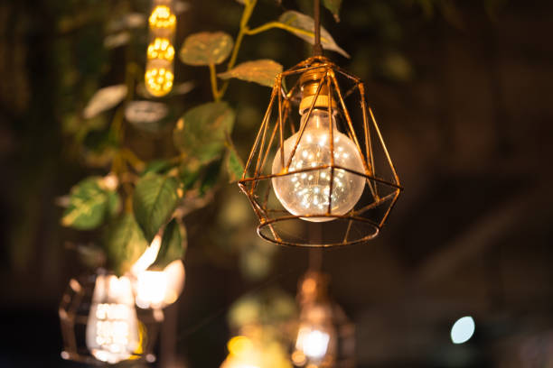 istock Ceiling lighting bulb with iron cage glowing in orange warm light. interior decoration. 2165704694