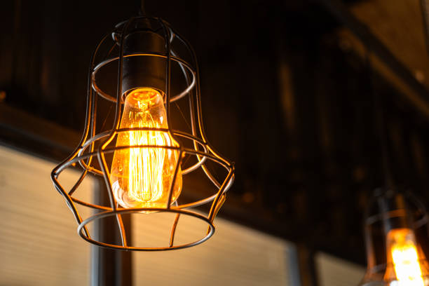 istock Ceiling lighting bulb with iron cage glowing in orange warm light. interior decoration. 2165704919
