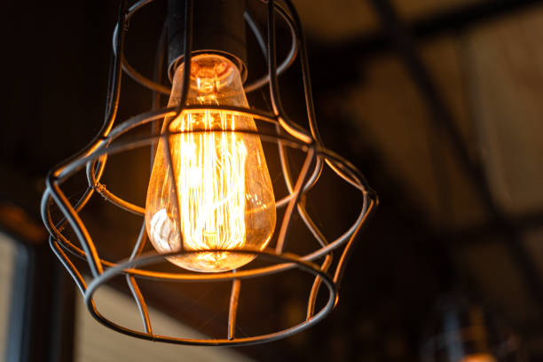 istock Ceiling lighting bulb with iron cage glowing in orange warm light. interior decoration. 2165704963