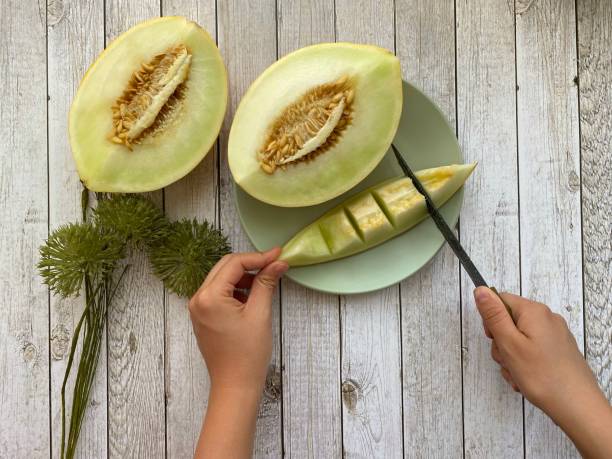 istock female hands and melon  on the white wooden table 2165707927