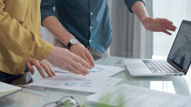 istock Business people, professionals analyzing financial charts and data on a desk while standing and using laptop computer in office 2165710230