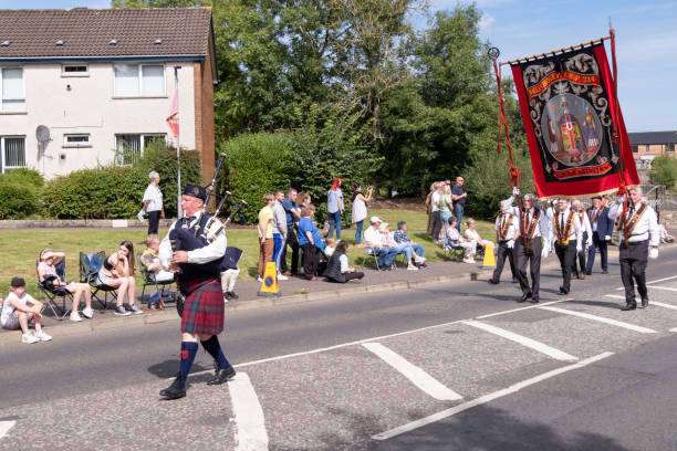 Ballyclare, UK - August 27th, 2022: lone piper in highland dress leads Ballyboley Royal Black Preceptory through town during annual Royal Black Institution last Saturday parade.