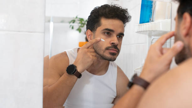 istock Handsome man uses facial cream in bathroom 2165714498