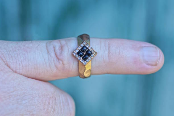 istock one old yellow gold ring with black gemstones on a finger 2165716076