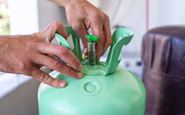 istock Technician hands adjusting valve on refrigerant tank during air conditioner maintenance. Professional HVAC service and repair, ensuring proper cooling system functionality 2165717737