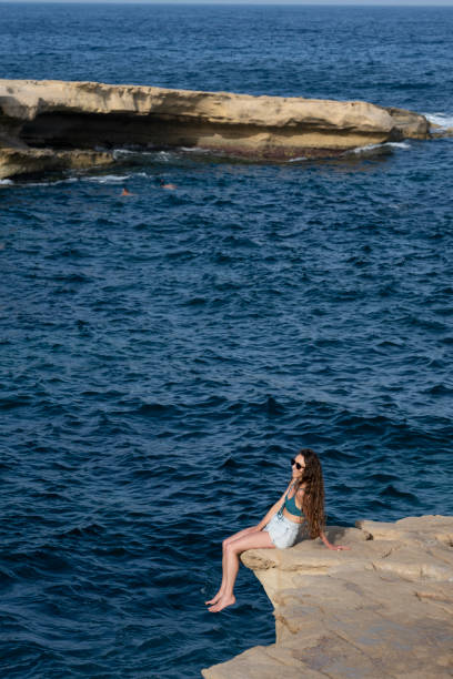 istock Woman explores cliff above sea, Gozo 2165725724
