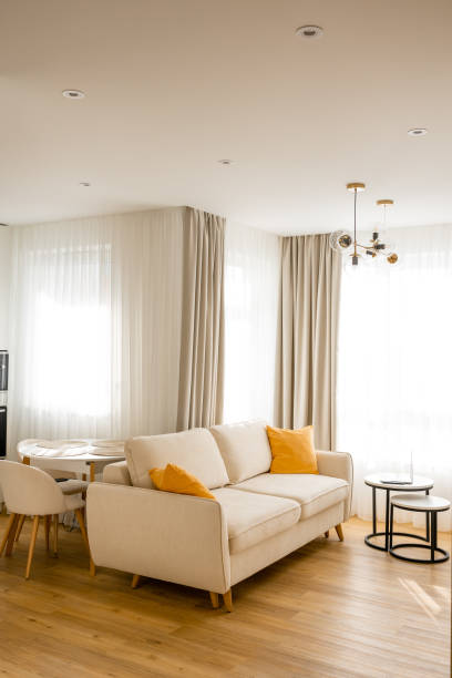 istock Interior of spacious luxurious living room with comfortable sofa next to bright windows at contemporary home 2165725779