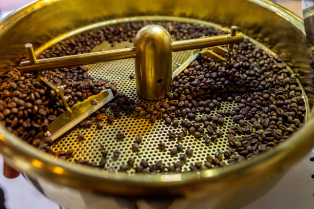 Close-up image of a small batch of freshly roasted coffee beans cooling on a tray. The photo highlights the rich texture and deep color of the beans, capturing the crucial final stage in the roasting process where beans are cooled to preserve their flavor and aroma. Ideal for showcasing the artisanal nature of coffee production and the attention to detail in small-scale roasting operations.