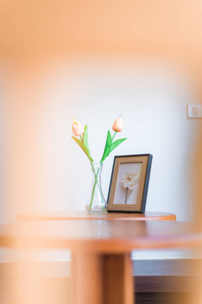 Interior composition. Wooden brown frame mock up, clay vase with brown dried flowers, stack of two old small books on a white coffee table against a white wall background.