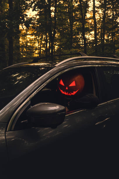 istock halloween concept man with pumpkin head in suv car 2165727233