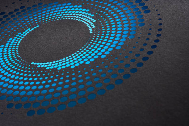 Native image size: 7952 x 5304. This captivating still life photograph presents an abstract circular paper artwork featuring a gradient of blue dots that transition smoothly from light to dark hues. Set against a dark background, the intricate design forms a mesmerizing pattern that draws the viewer's eye toward the center. The precision of the cutouts and the play of light and shadow enhance the three-dimensional effect, highlighting the meticulous craftsmanship involved. This image beautifully combines modern geometric design with the delicate medium of paper art.