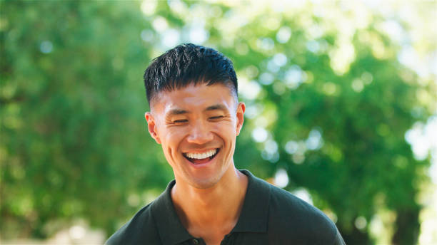 Young Man Laughing Outdoors in a Sunlit Park During a Summer Day