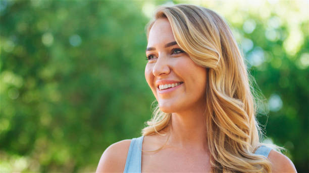 istock Smiling Woman in Blue Top Outdoors on a Sunny Day 2165731114