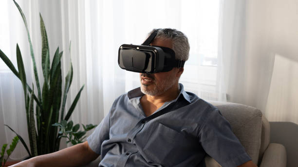 istock Senior man using VR glasses at home 2165732694