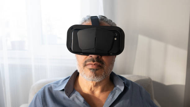 istock Senior man using VR glasses at home 2165732720