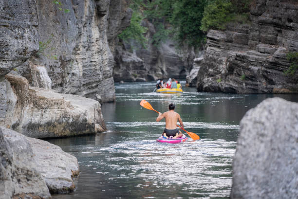 Rear view of Mature man Using Stand Up Paddle Board at canyon river, Water Sports, Healthy Living Activity, Man’s Lifestyle