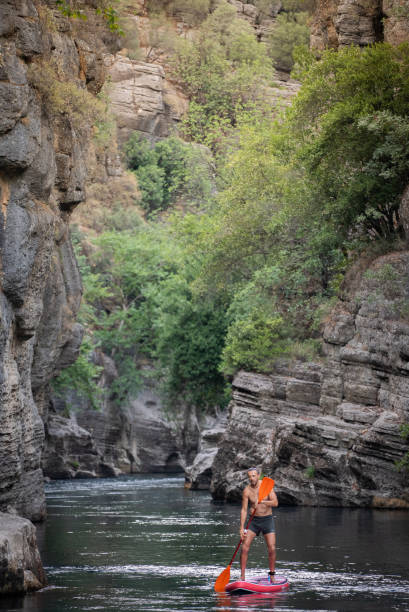 istock Mature men floating on SUP in Canyon 2165738970