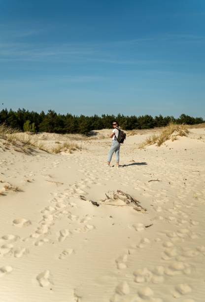 istock Woman hiking through sandy dunes with a backpack under a clear blue sky in Poland 2165740038
