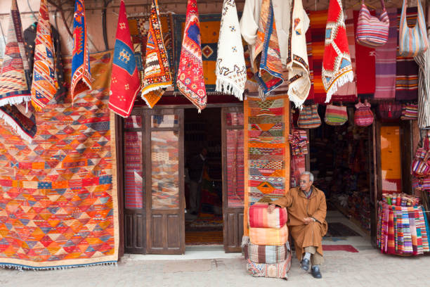 Young male and female couple walking past vibrant Moroccan carpets and historic architecture in the ancient city of Marrakesh