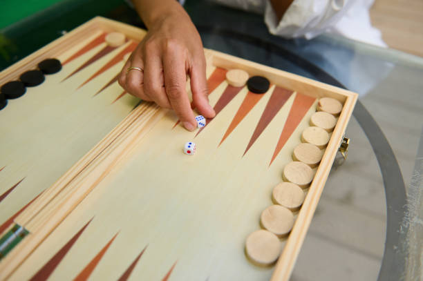 istock Hand rolling dice on a wooden backgammon board during a strategic game 2165764042