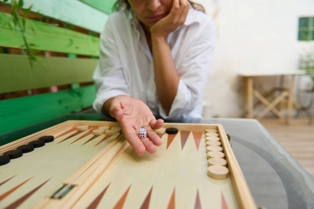 istock Person playing backgammon with dice in hand, contemplating next move 2165764043