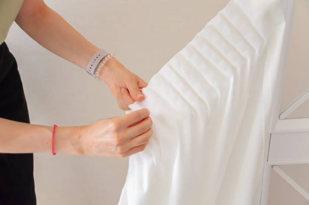 istock Women's hands in a close angle put hooks on the ribbon on the curtains. 2165775855
