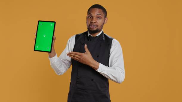 istock Restaurant waiter presenting a green screen layout on tablet 2165778222