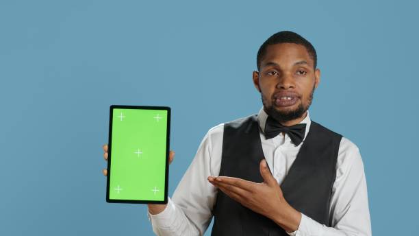 istock Bellman hotelier showing a tablet with green screen display in studio 2165778821