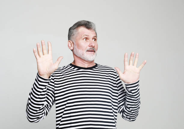 istock Surprised joyful elderly man with a gray beard raises his hands in amazement. 2165782188